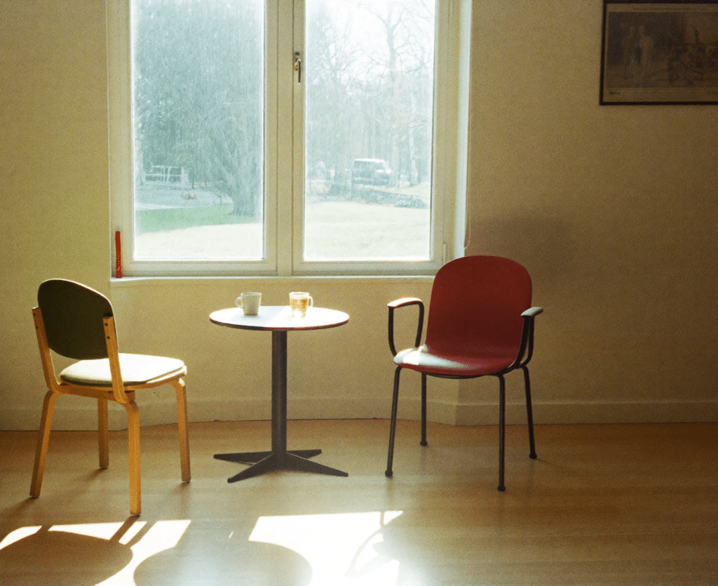 Two chairs and mugs of tea at a small table by a bright window